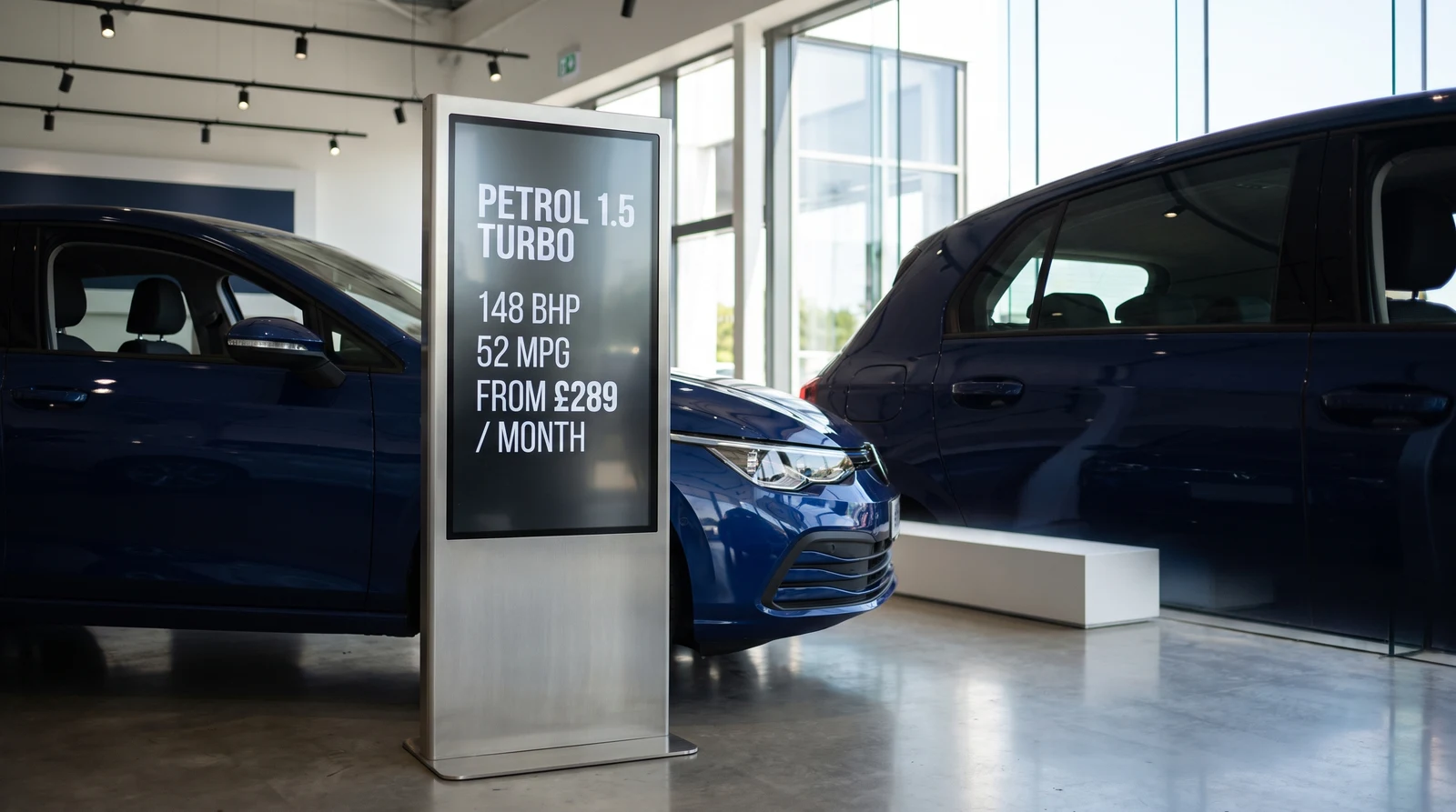 Slim portrait screen on a stand beside a car in a dealership showroom displaying the vehicle spec and a monthly finance figure