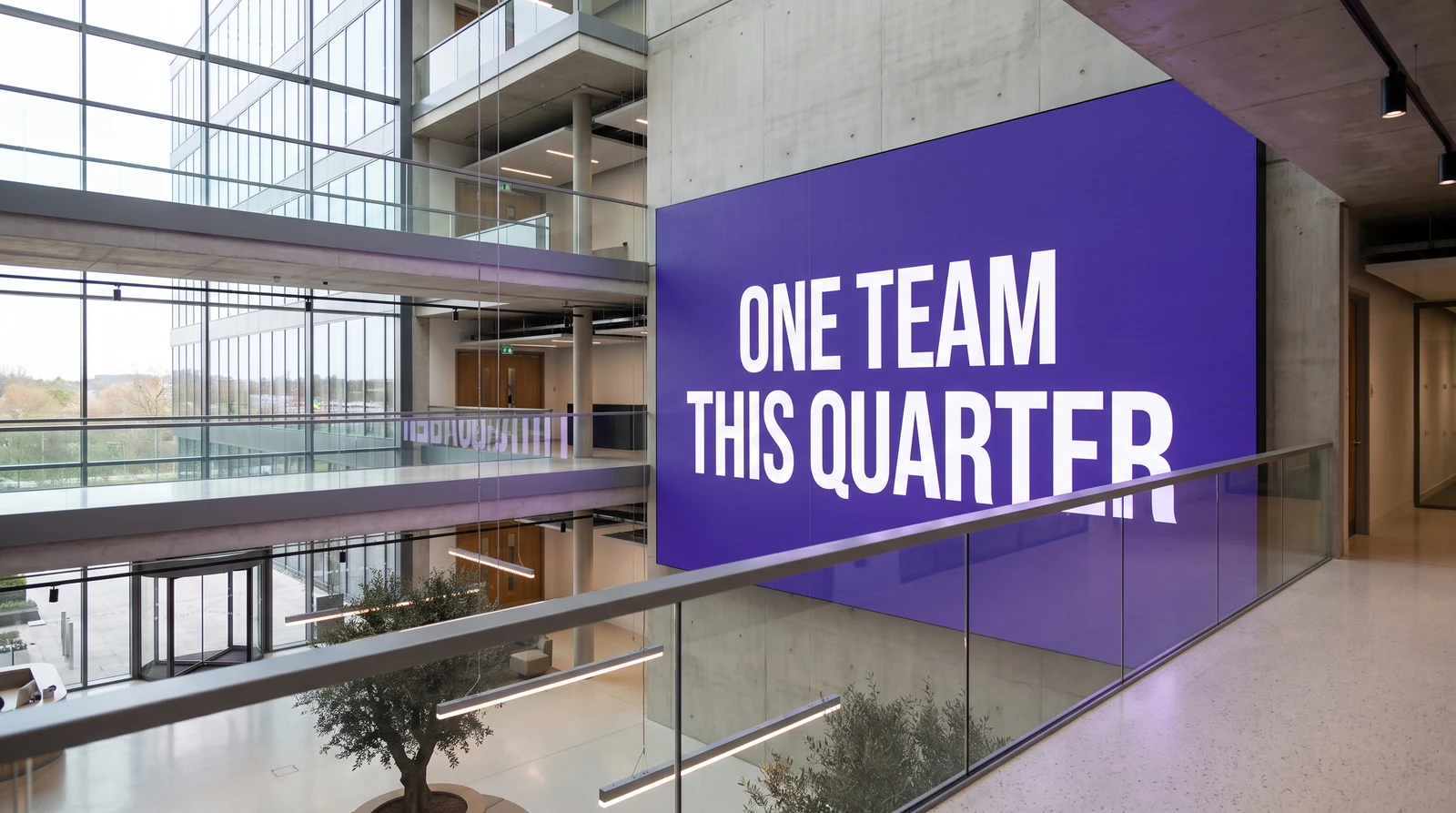 Large screen on the wall of a multi-floor corporate atrium showing a company-wide message