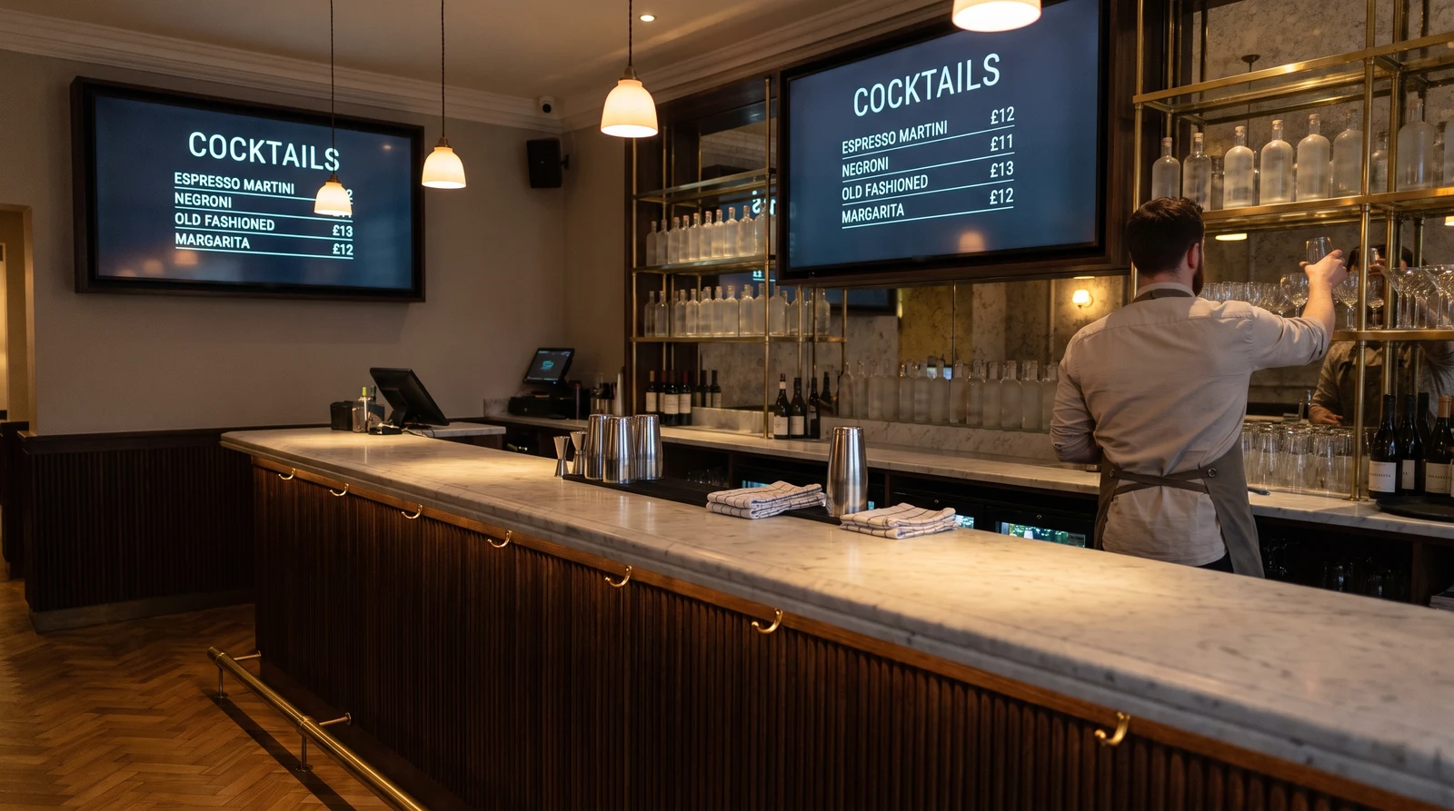 Cocktail bar with two digital menu boards above the back bar showing the cocktail list and prices