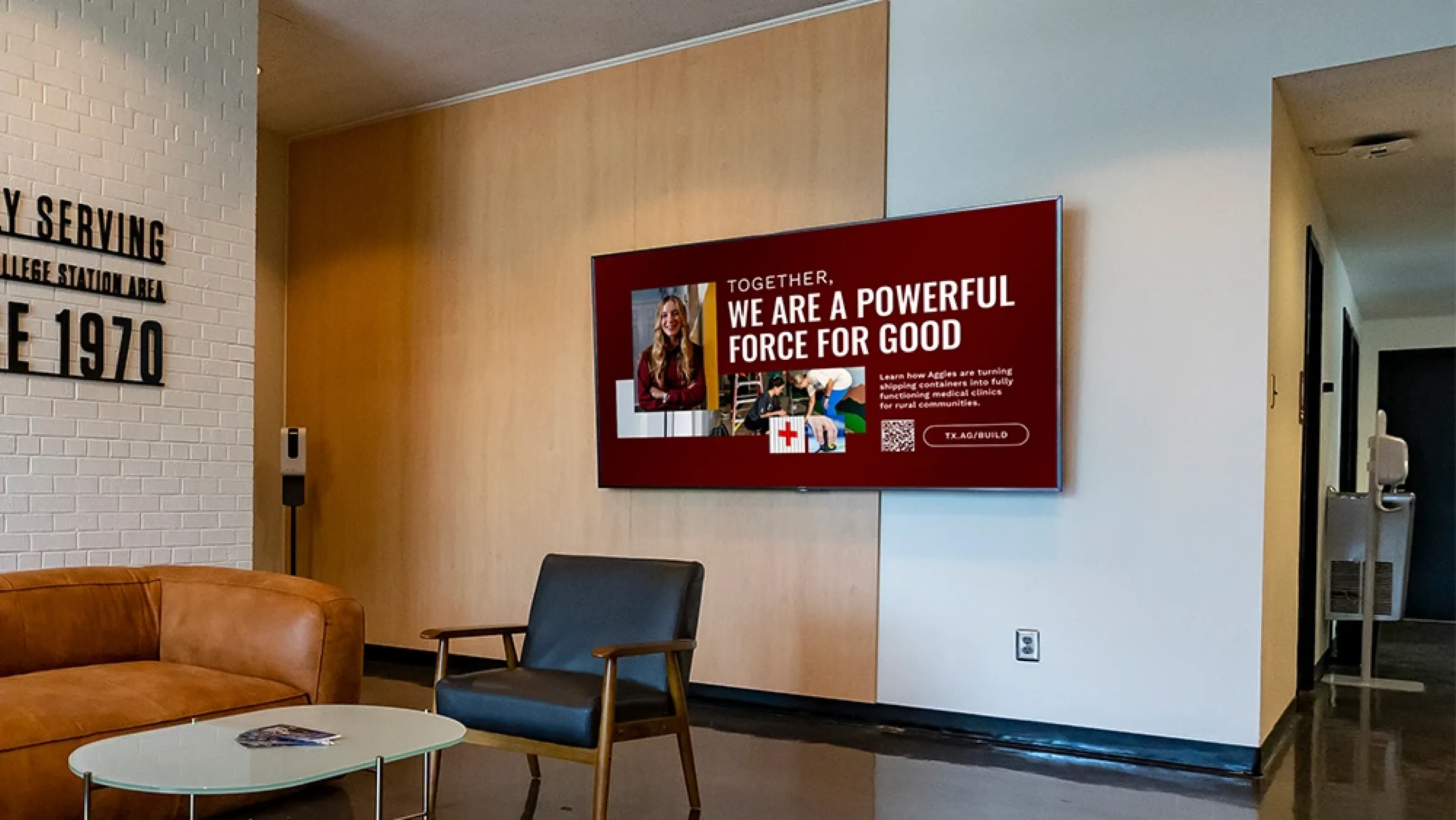 A wall-mounted lobby screen playing a designed digital poster, the kind of design you would make in a tool like Canva.