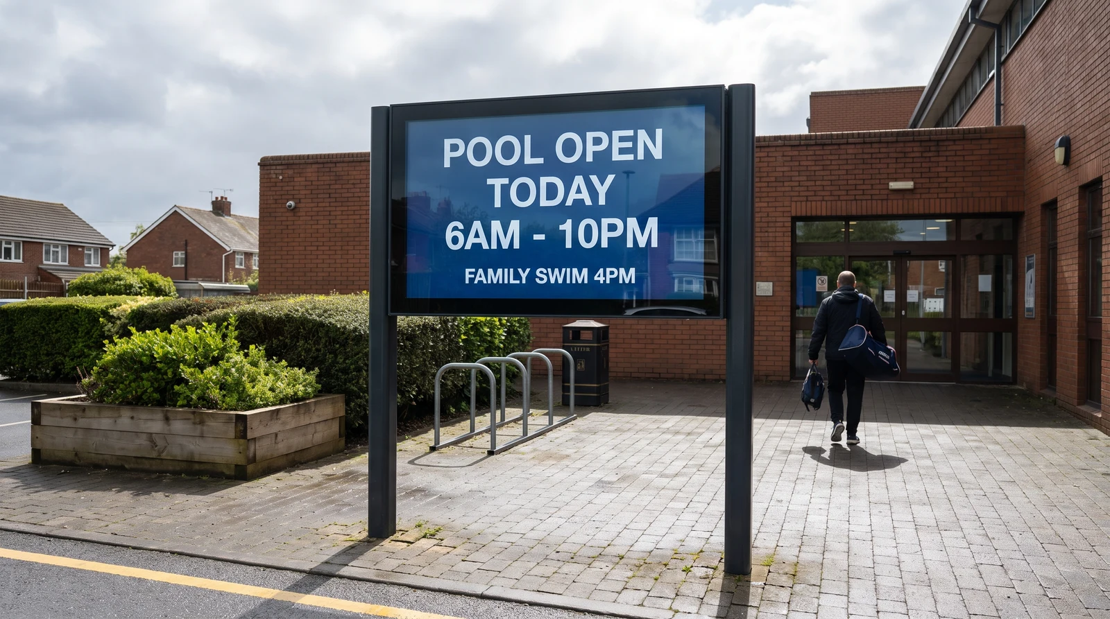 Outdoor digital reader board on posts at a community leisure centre entrance showing today's opening hours