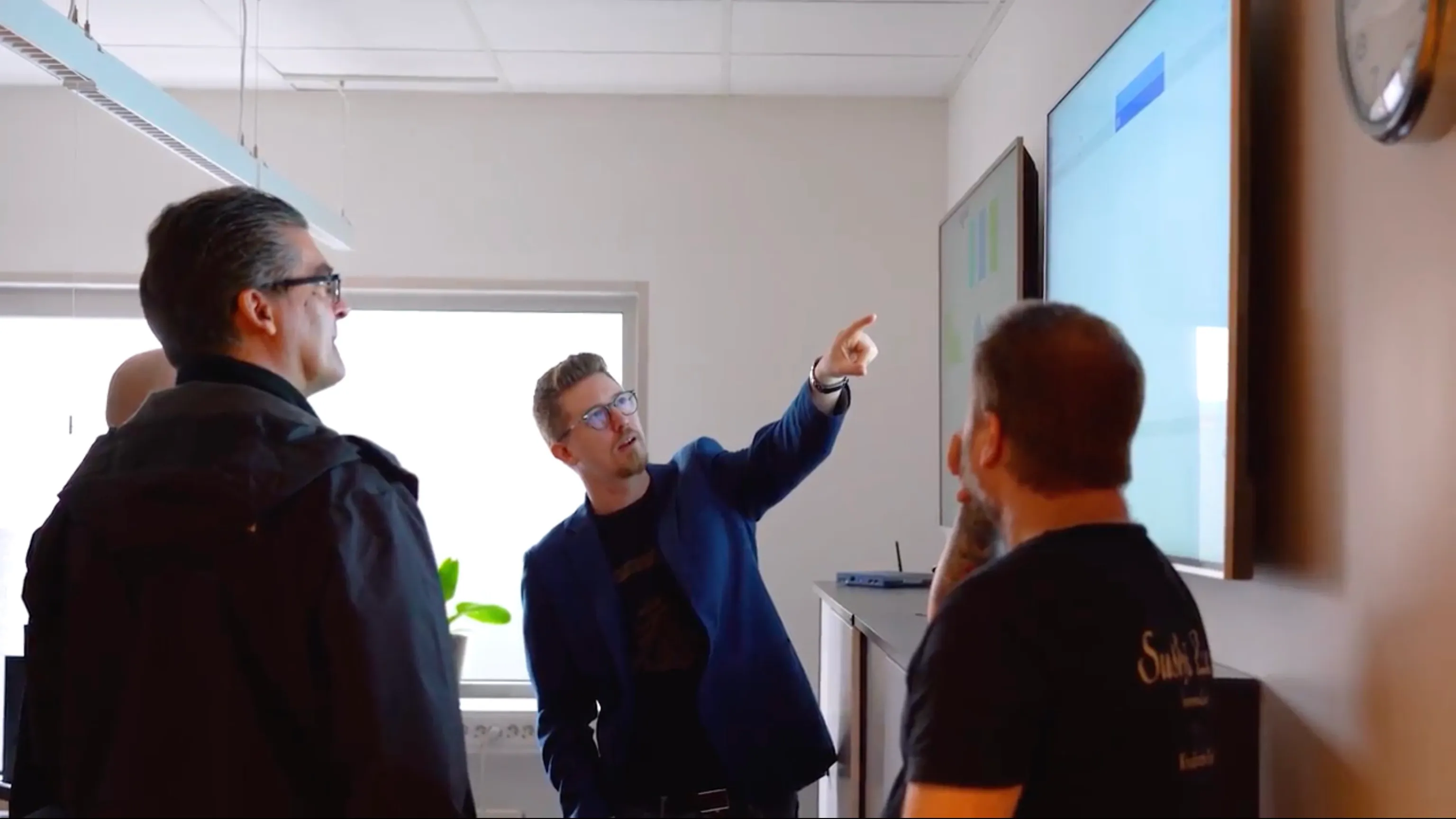 A team reviewing data on a wall-mounted TV display in an office workspace