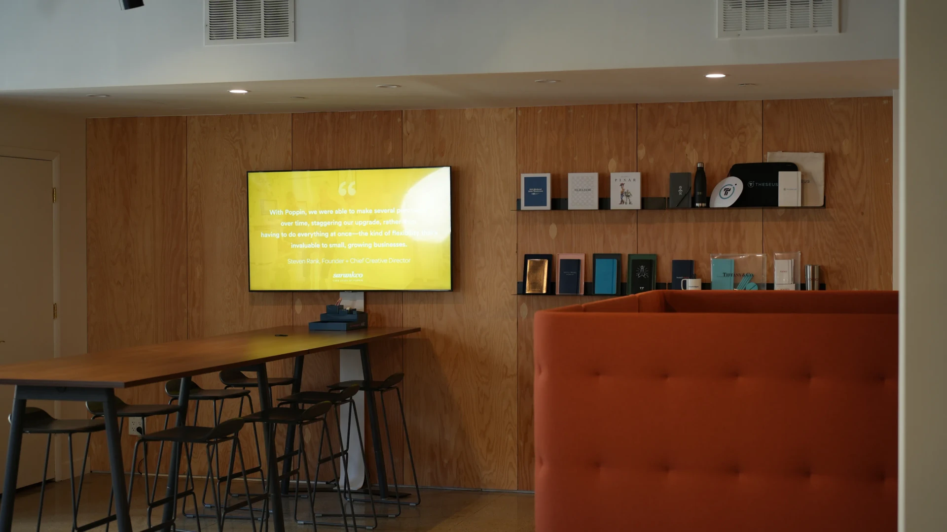 Modern bank branch with digital signage screens showing financial products, exchange rates, and customer service queue