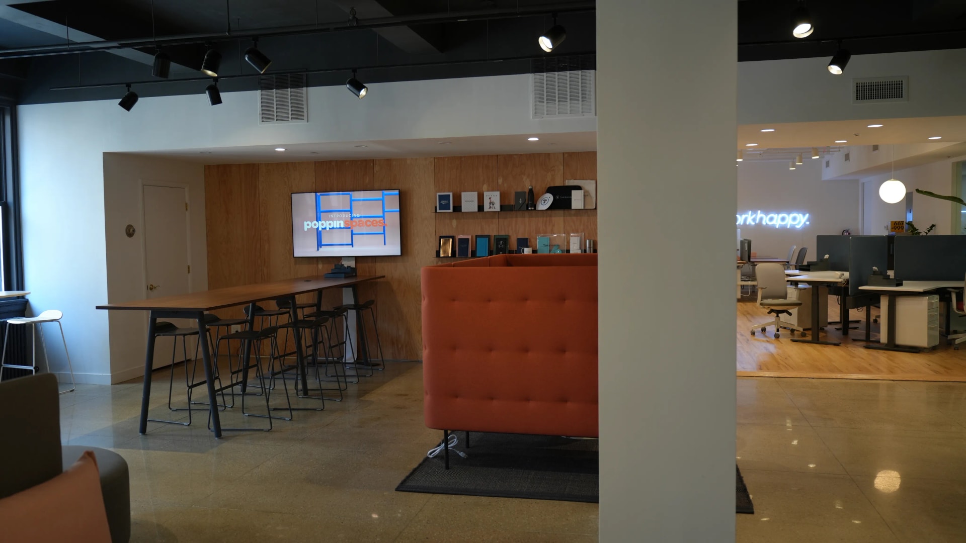 Office lounge with a wall-mounted TV showing branded digital signage content