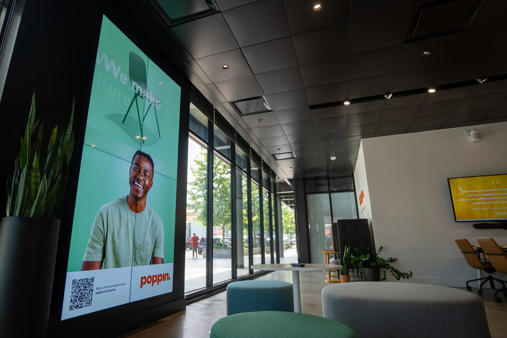 Large portrait screen in a street-level customer waiting area showing a product promotion and a QR code