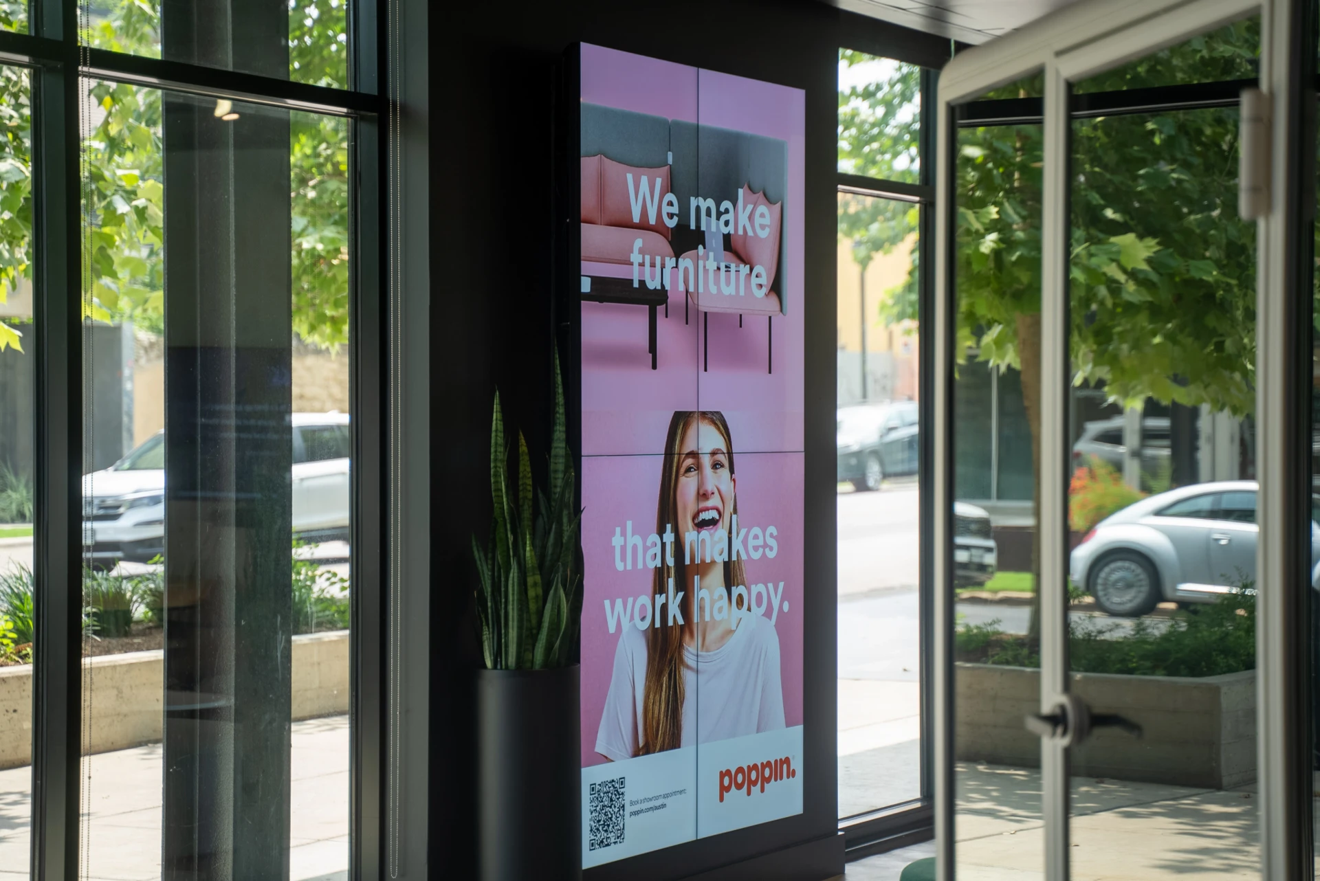 Poppin retail storefront portrait video wall displaying a pink branded campaign with QR code