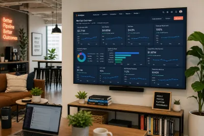Revenue operations office area with a HubSpot revenue overview dashboard on a wall-mounted TV, alongside a Better Pipeline Better Outcomes neon sign