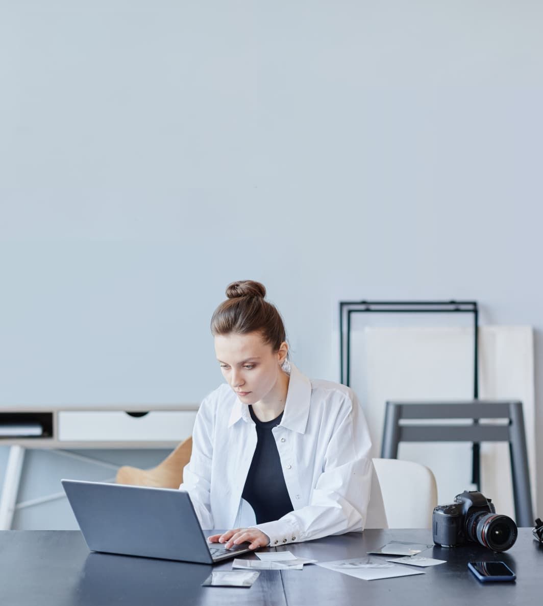 A woman sits at a desk in an office, working on her laptop. UI elements of Fugo's digital signage solution are overlain on the photo.